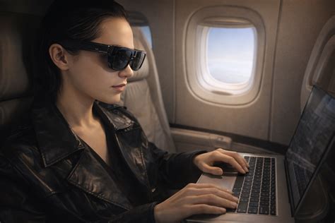 Person using XReal AR glasses with a laptop while travelling